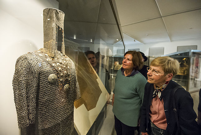 Zwei Besucherinnen schauen sich ein Kettenhemd der so genannten Karlsruher Türkenbeute an.