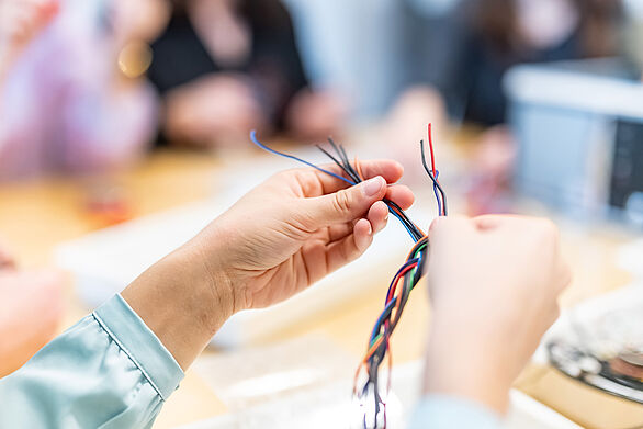 Zwei Hände flechten mit alten Elektrokabeln