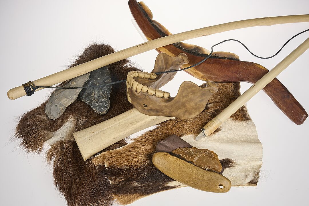 Arrangement aus Fell, Faustkeil, Bogen und Kieferknochen